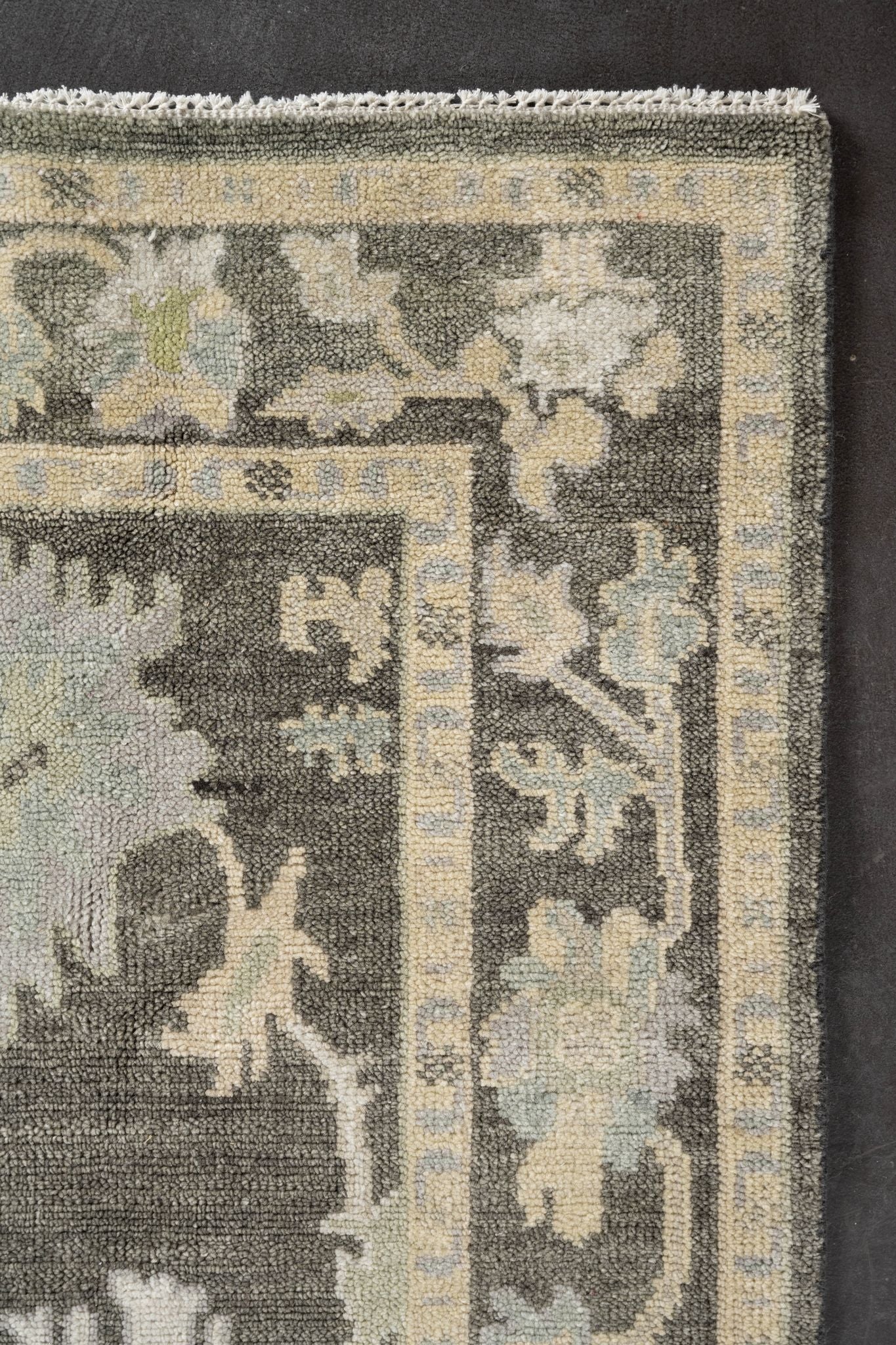 Neutral toned and hand-knotted Oushak style rug made of 100% New Zealand wool. This rug is comprised of beige, tan, charcoal, brown, and ivory colors.