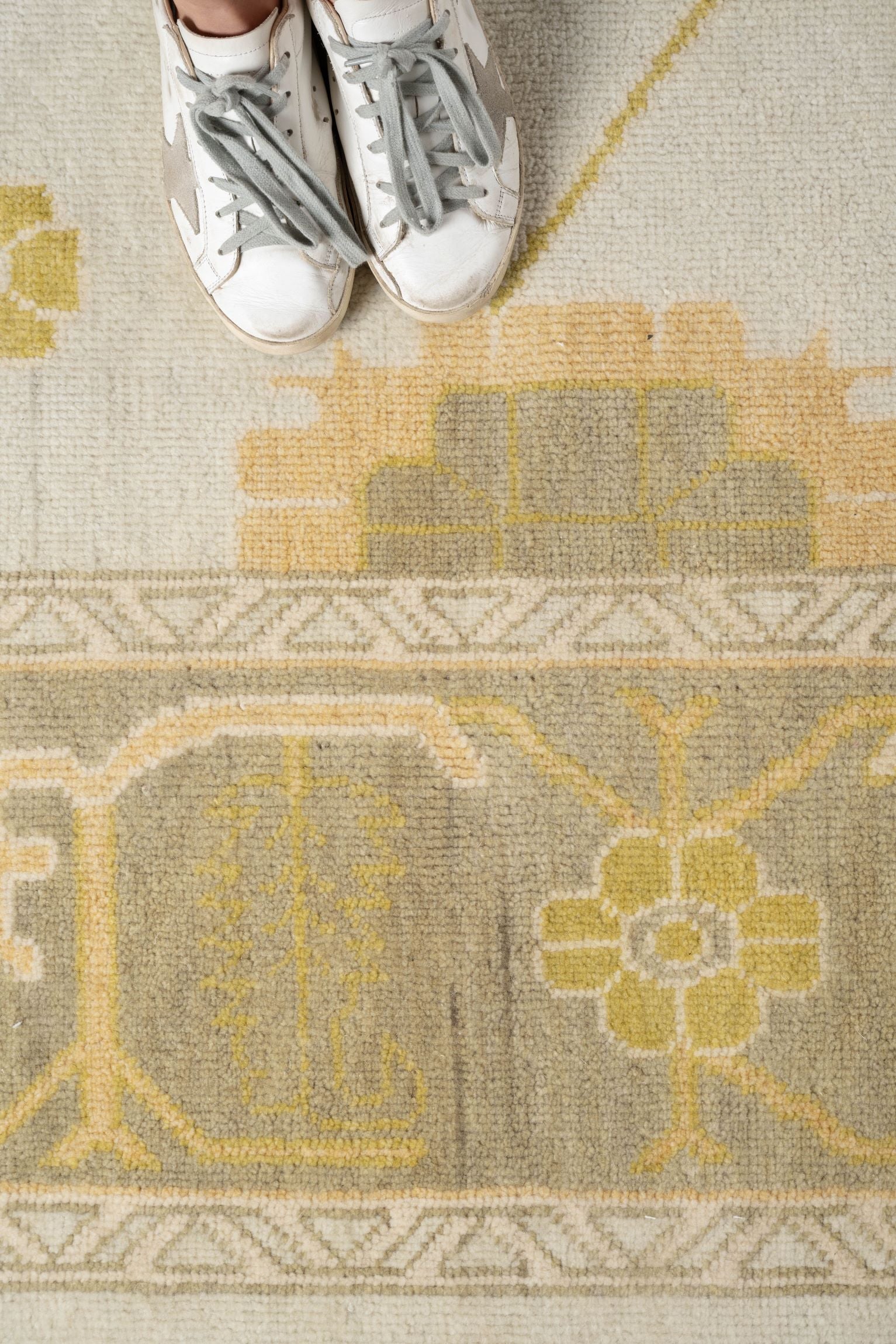 Neutral toned and hand-knotted Oushak style rug made of 100% New Zealand wool. This rug is comprised of tan, taupe, yellow, gold, blue, navy, gray, and ivory colors.