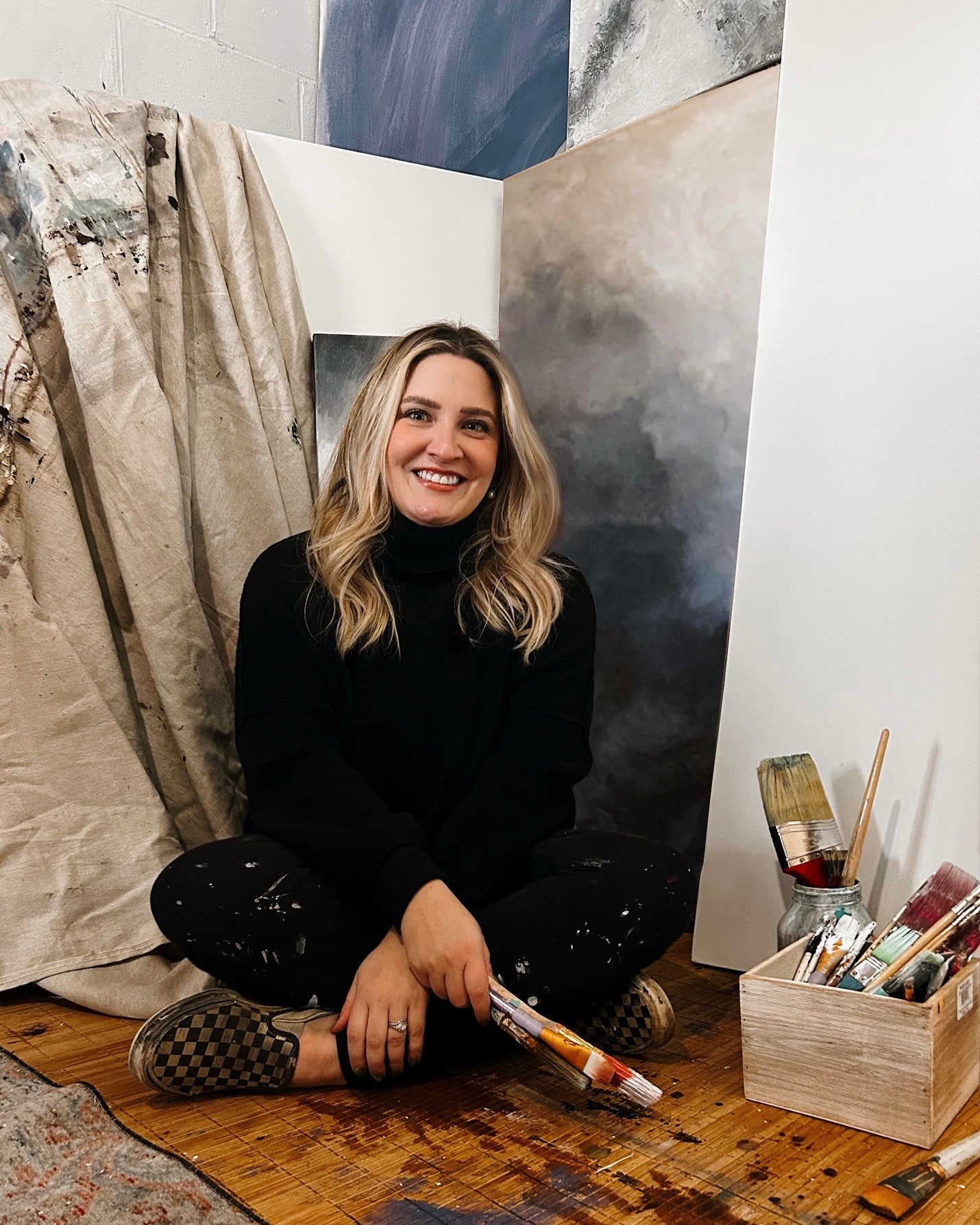 woman sitting on art mat, smiling at camera