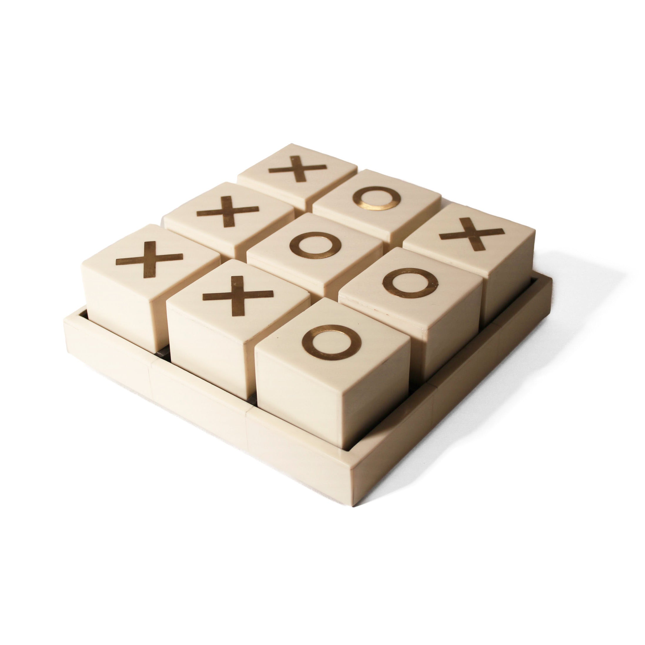 A decorative game of tic tac toe with a bone tray serving as the playing board and cubes with brass X's and O's.  