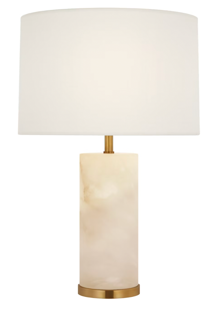 A modern table lamp with a large white drum shade, a cylindrical cream-colored marble base, and polished gold-finished metal accents at the neck and bottom.