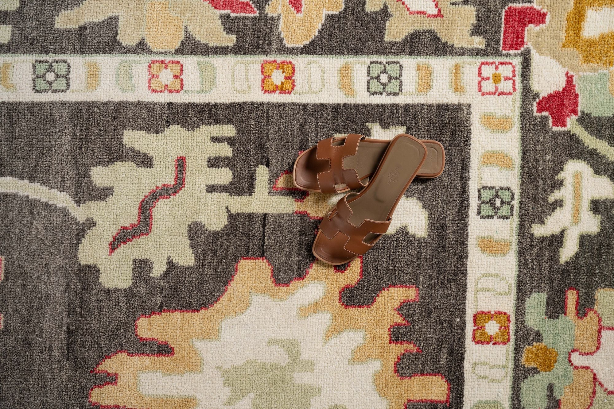 top down view of brown sandals on a patterned rug